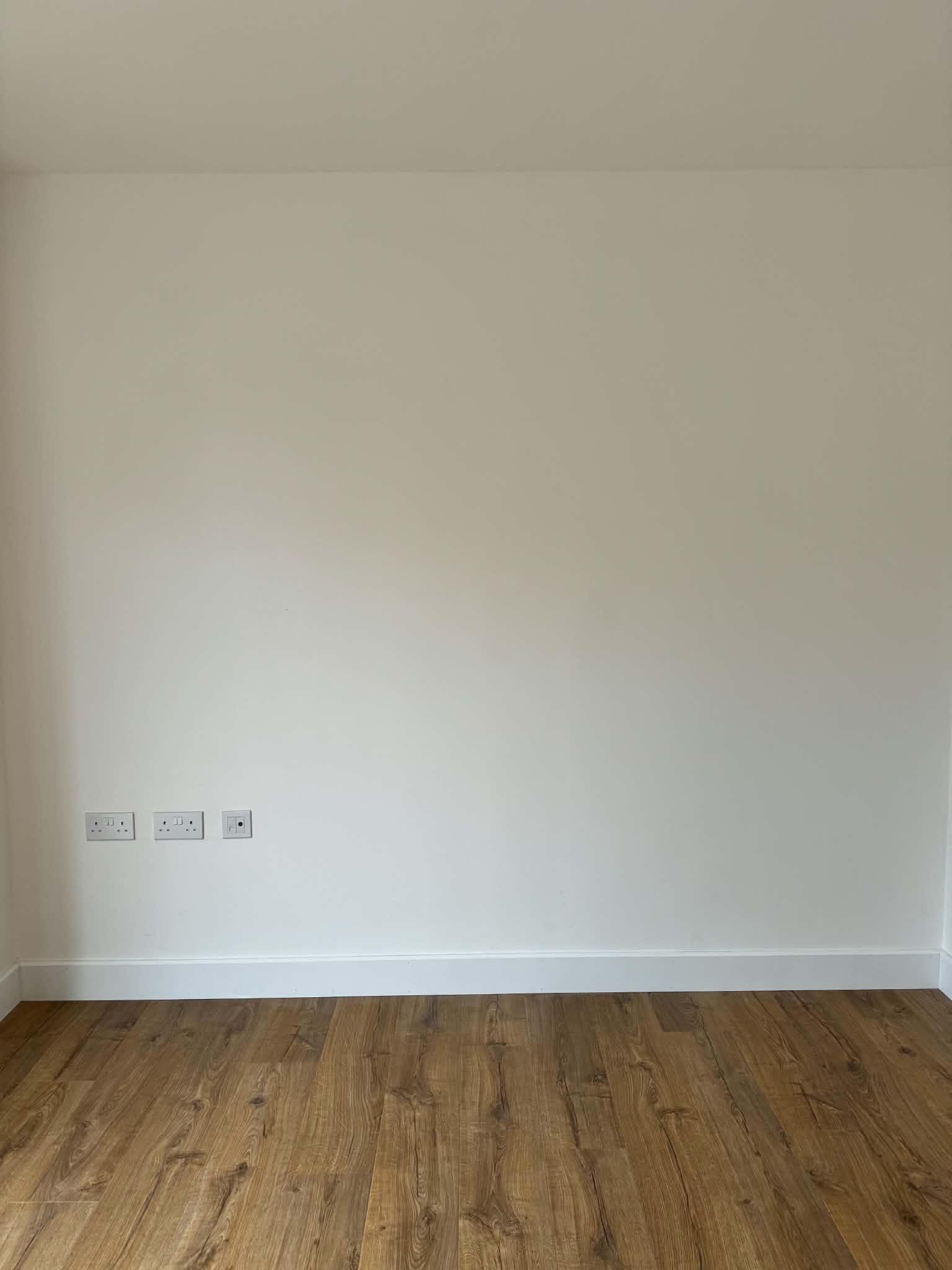 Finished timber flooring next to a white wall