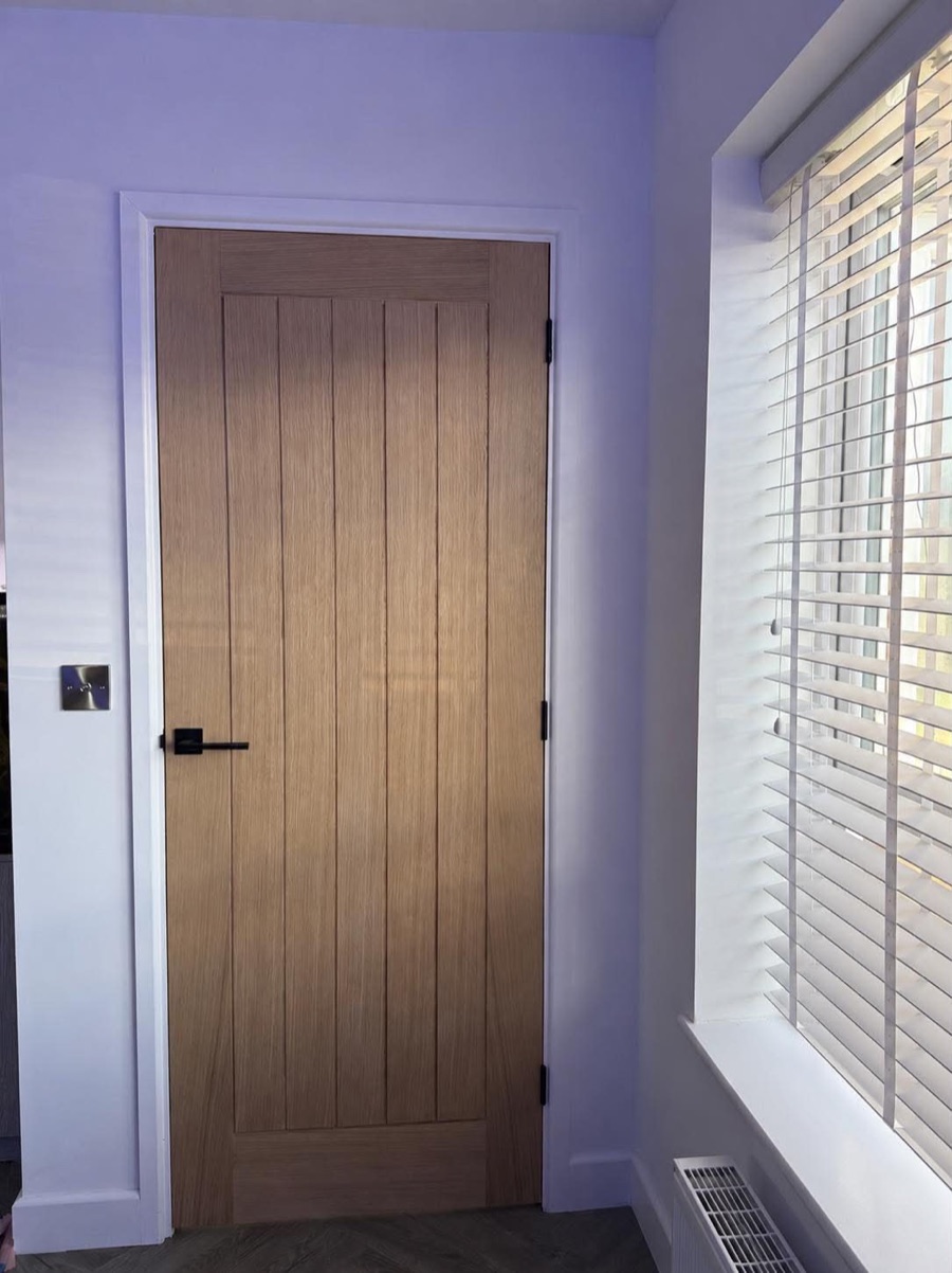 Oak internal door fitted with black handle and white frame
